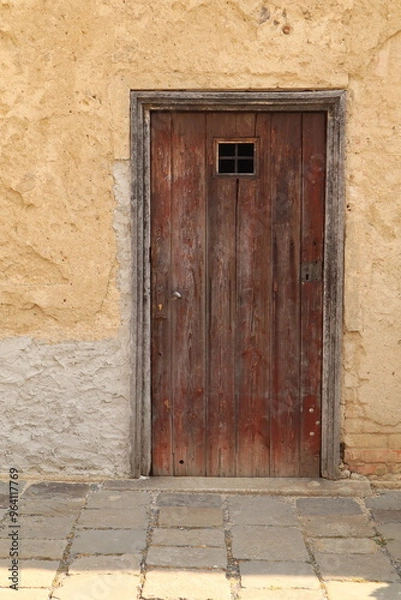 Obraz small, rectangular wooden door in a wall. 