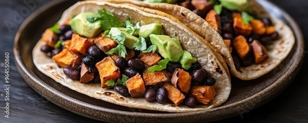 Obraz Delicious tacos filled with black beans and sweet potatoes topped with fresh herbs and avocado, perfect for a healthy meal.