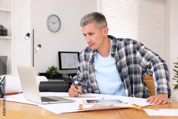 Fototapeta Architect making engineering drawing at wooden table in office