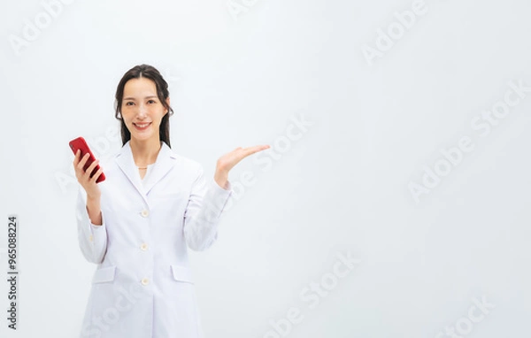 Fototapeta スマホを持って案内する白衣の女性