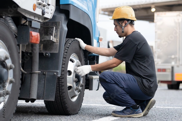Obraz トラックのタイヤを点検する男性