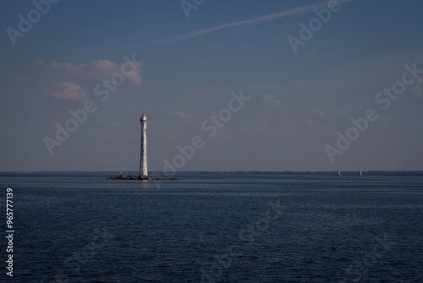 Fototapeta View of the lighthouse and the sea illuminated by the sun and clouds
