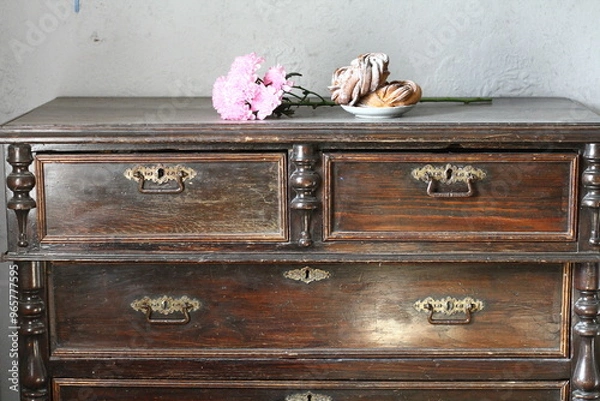 Fototapeta Still life with flowers and butterflies on an old chest of drawers on a blurred gray background