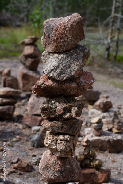 Fototapeta Stone on stone stacked on top of each other in the sun on a blurred green background of grass