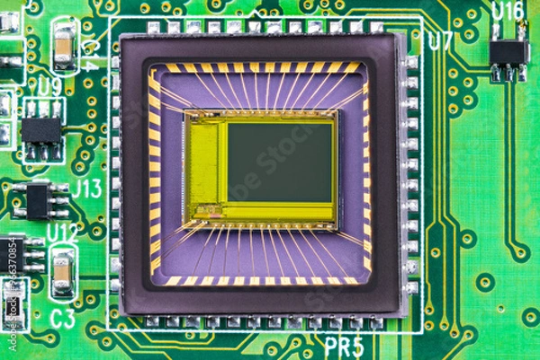 Fototapeta Closeup of image sensor on printed circuit board inside digital camera. Small die and gold wires in integrated chip transparent package of imager with semiconductor electronic components on green PCB.