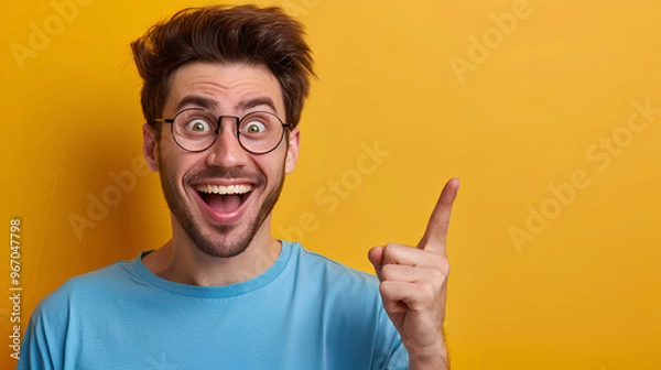 Fototapeta A man with glasses is pointing at something and smiling