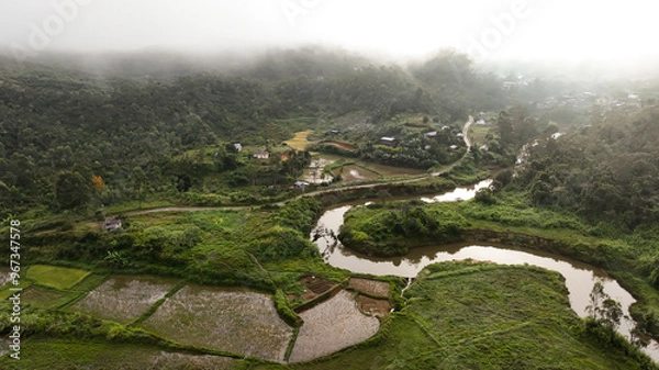 Fototapeta Aerial view of Andasibe landscape showcasing lush greenery, winding river, and rice paddies in Madagascar at dawn