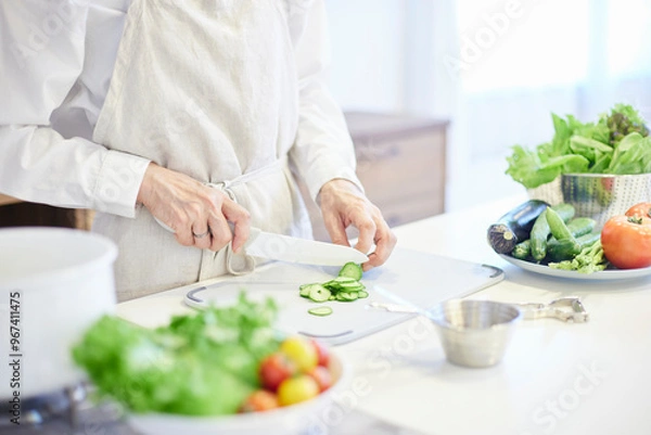 Fototapeta キッチンにて料理をするエプロンを着た日本人シニア女性