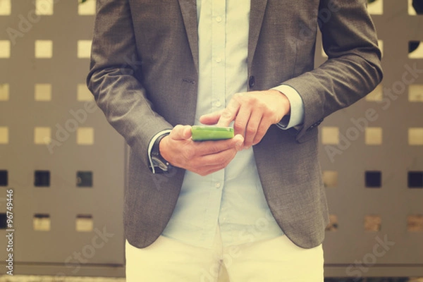 Obraz Elegant man using cellphone outdoors.