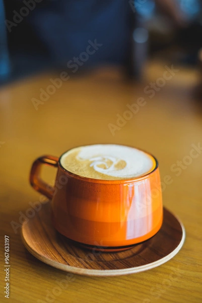 Fototapeta A warm cup of coffee on a saucer in a cafe setting.