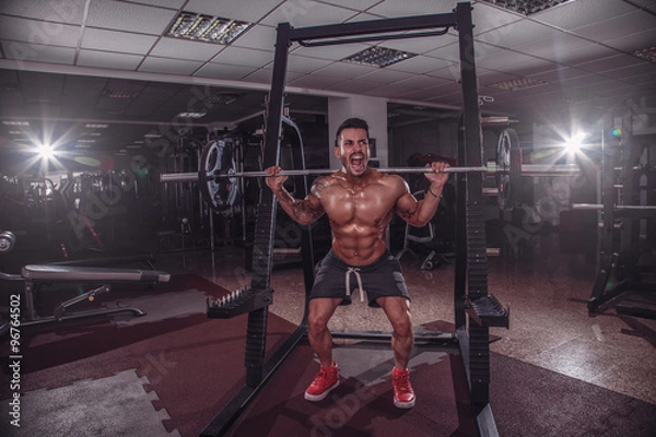 Obraz Strong man doing squats in the gym.
