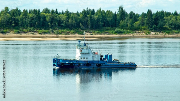 Fototapeta A large river vessel pulls two barges loaded with timber down the river