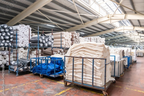 Fototapeta Fabric warehouse with lots of fabric rolls and stacks of fabrics in a textile factory.