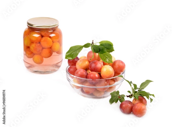 Fototapeta Jar of cherry plum compote and fresh plums in a glass container on a white background