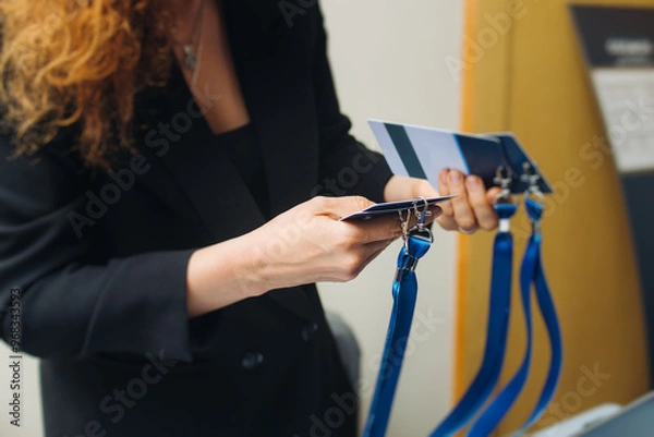 Fototapeta Process of checking in on conference congress forum event, registration desk table, visitors and attendees receiving lanyard with name badge and entry wristband bracelet and register electronic ticket