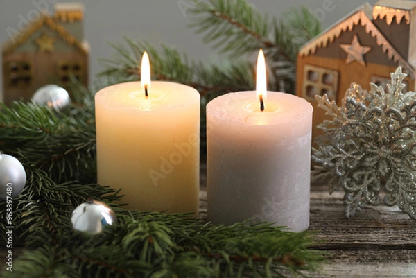 Fototapeta Burning candles, baubles and fir tree branches on wooden table, closeup