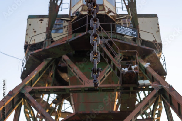 Fototapeta Closeup of a rusty chain on an old industrial harbor crane, highlighting the wear and age of the metal components