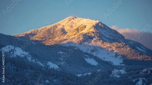 Obraz A majestic snow-covered mountain basking in warm sunlight during a serene winter evening.
