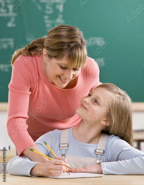 Obraz Teacher explaining homework to student in school classroom