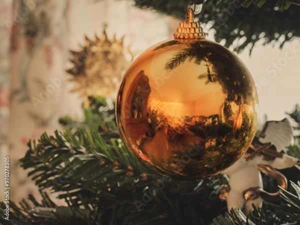 Fototapeta Gold yellow Christmas ball ornament decorative item is hung on Christmas green tree with bokeh light,