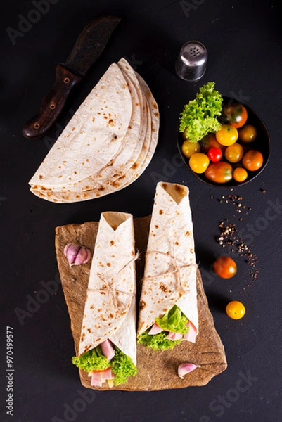 Fototapeta wrap sandwich with ham, lettuce, tomatoes and cheeses