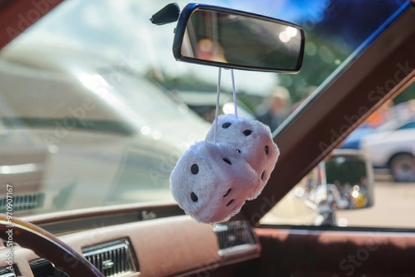 Fototapeta Two white furry dice under the rear view mirror of a classic American retro oldtimer car as a luck symbol.