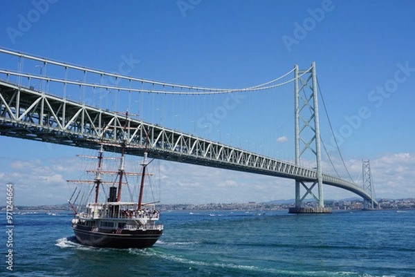 Obraz 晴天の海にかかる巨大な吊橋と帆船