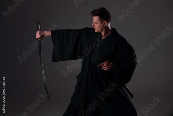 Fototapeta Samurai ninja warrior in kimono in attack pose with katana sword. dark room. sword shine. fighter. japanese culture