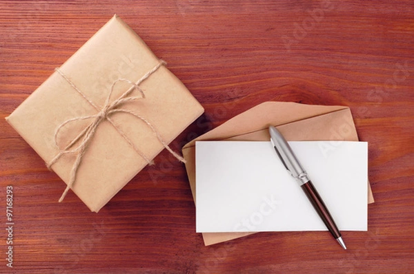 Fototapeta Gift box and envelope with blank paper sheet and pen on wooden table