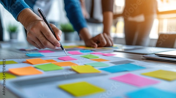 Obraz collaborative team working together around a table, hands visible, using sticky notes to brainstorm ideas. The scene emphasizes teamwork, creativity, and problem-solving