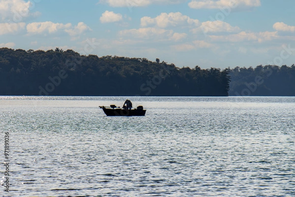 Fototapeta silhouette of man fishing in small boat on northern lake
