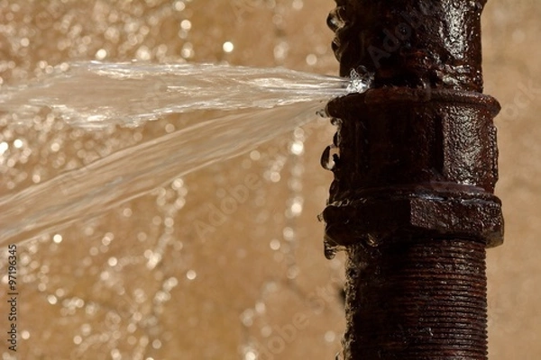 Fototapeta Rusty burst pipe squirting water at high pressure