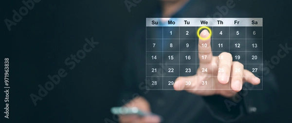 Fototapeta Planning and time management concept. A man manages his time using virtual screen calendar interface to highlight the date to remind him about important work, meeting, or agenda