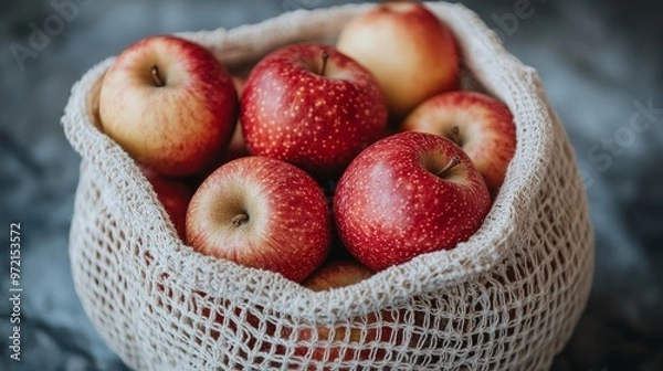 Fototapeta Red apples in beige mesh bag lying on dark textured surface