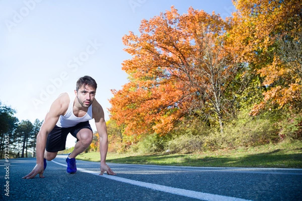 Obraz man in athletic start position outside