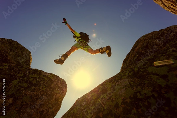 Obraz man jumping cliff with blue sky