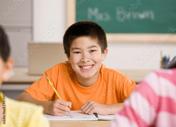 Fototapeta Happy student writing in notebook in school classroom
