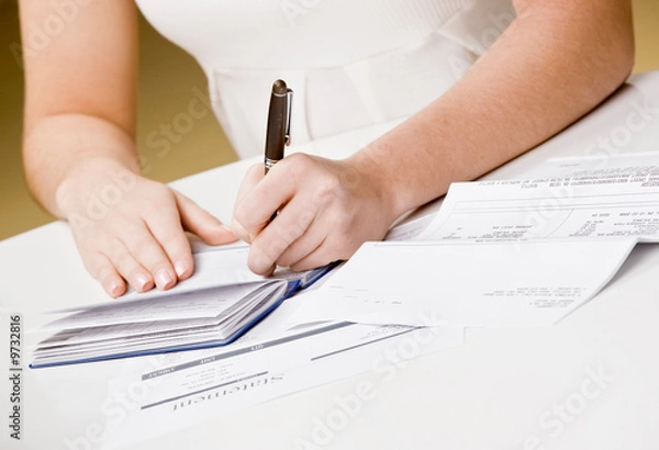 Fototapeta Kobieta pisze czeki z książek czekowych do płacenia miesięcznych rachunków