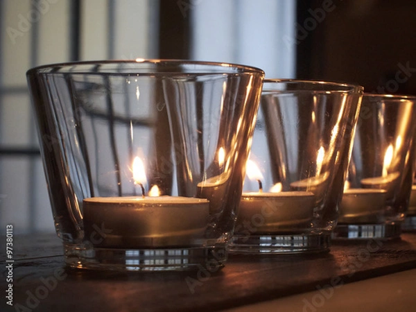 Obraz lit candles in glasses on rustic wooden shelves
