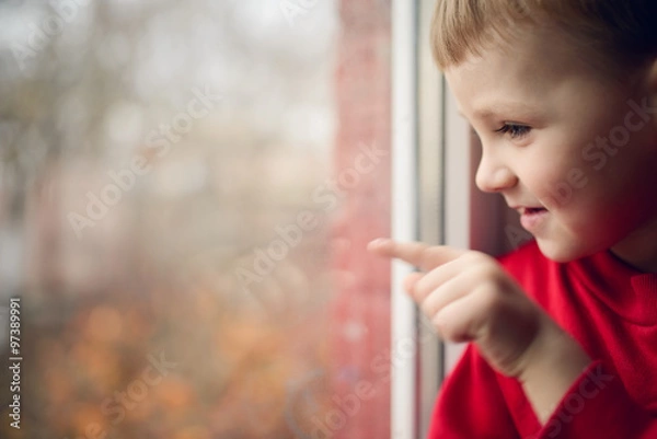 Fototapeta small boy sitting near window and thnking about something