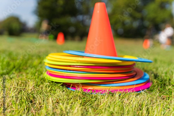 Fototapeta Background with a red cone and colorful game circles in the grass. Children's game concept