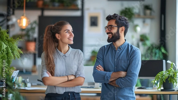 Fototapeta Business Discussion,  Two young professionals engage in a conversation at a minimalist office, displaying focused expressions and showcasing a collaborative work environment