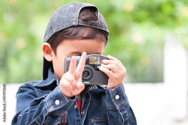 Obraz Cute boy using compact camera with showing two fingers.