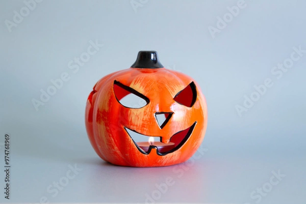 Obraz Ceramic Halloween pumpkin with lit candle flame against a silver grey background