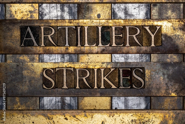 Fototapeta Artillery Strikes text in real authentic typeset letters on vintage textured silver grunge copper and gold background
