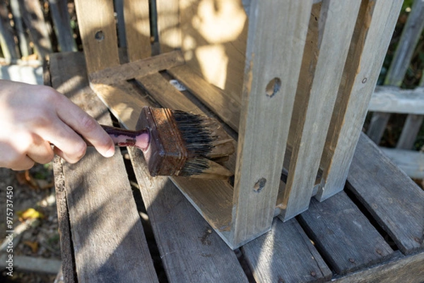 Obraz a child paints a wooden box with brushes in the garden