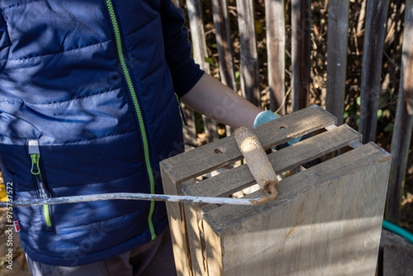 Obraz a child paints a wooden box with brushes in the garden