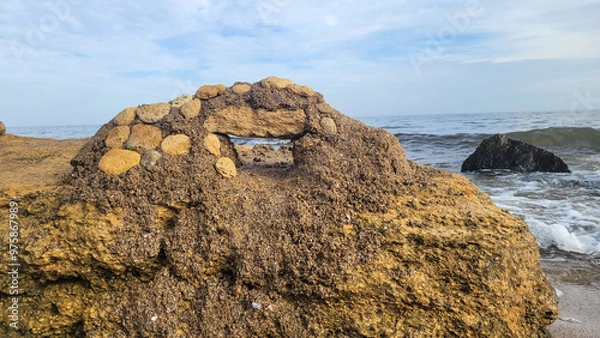 Fototapeta A structure made of stones and sand on the Black Sea coast. The sea with black stones in the background