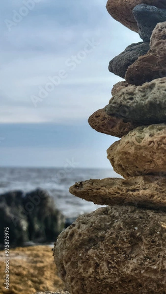 Fototapeta A stone structure close up on the Black Sea coast. The sea with black stones in the background is blurred