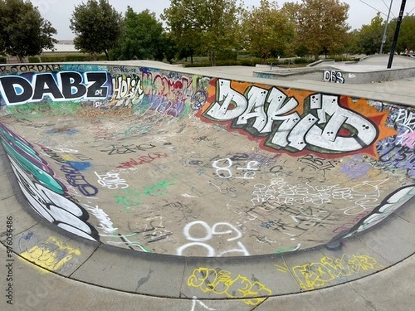 Fototapeta a vibrant painting of a graffiti-covered skatepark flow bowl features bold colors and dynamic designs, showcasing skateboarding culture in an urban, creative space